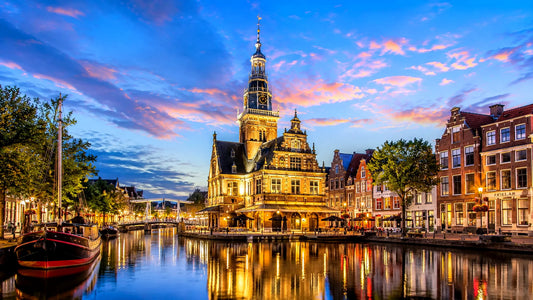 “Breedbeeldfoto van de historische binnenstad van Alkmaar, Nederland, met karakteristieke grachten, bruggen en traditionele Hollandse architectuur – sfeervolle 8K landmarkfoto voor meubels herstofferen en meubelstoffering in Alkmaar.”